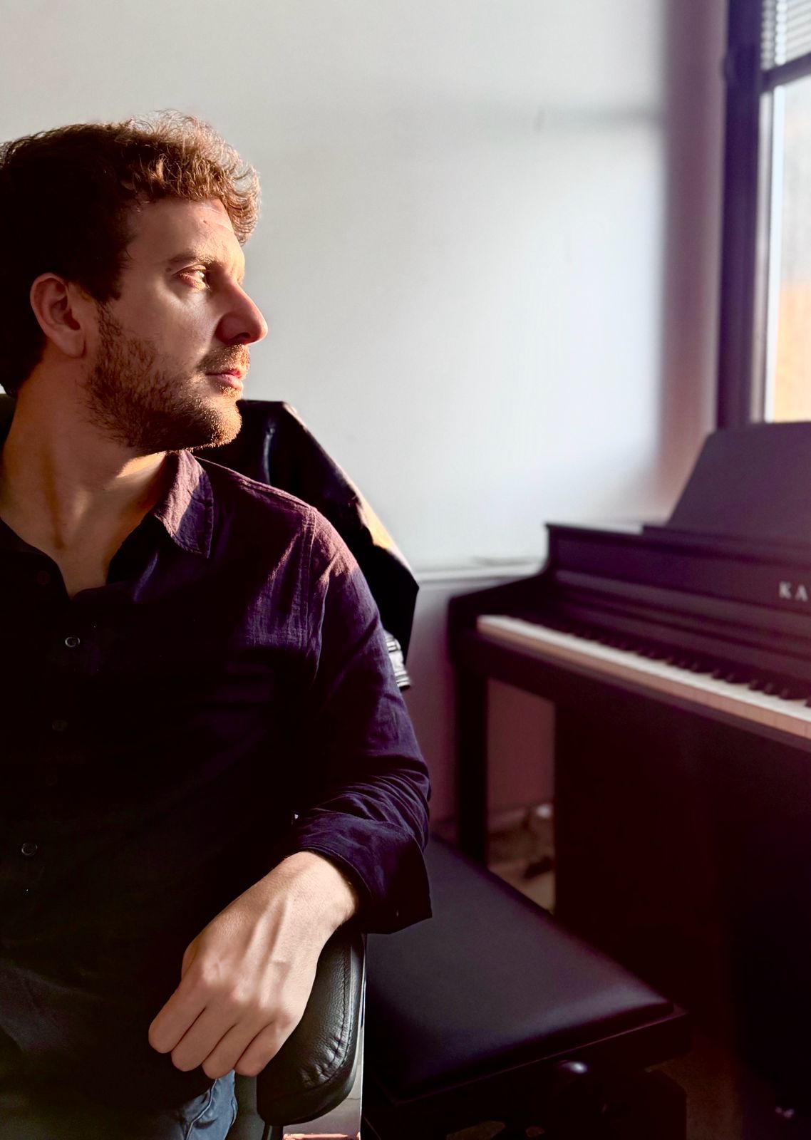 Michele Bargigia accanto al pianoforte vicino alla finestra