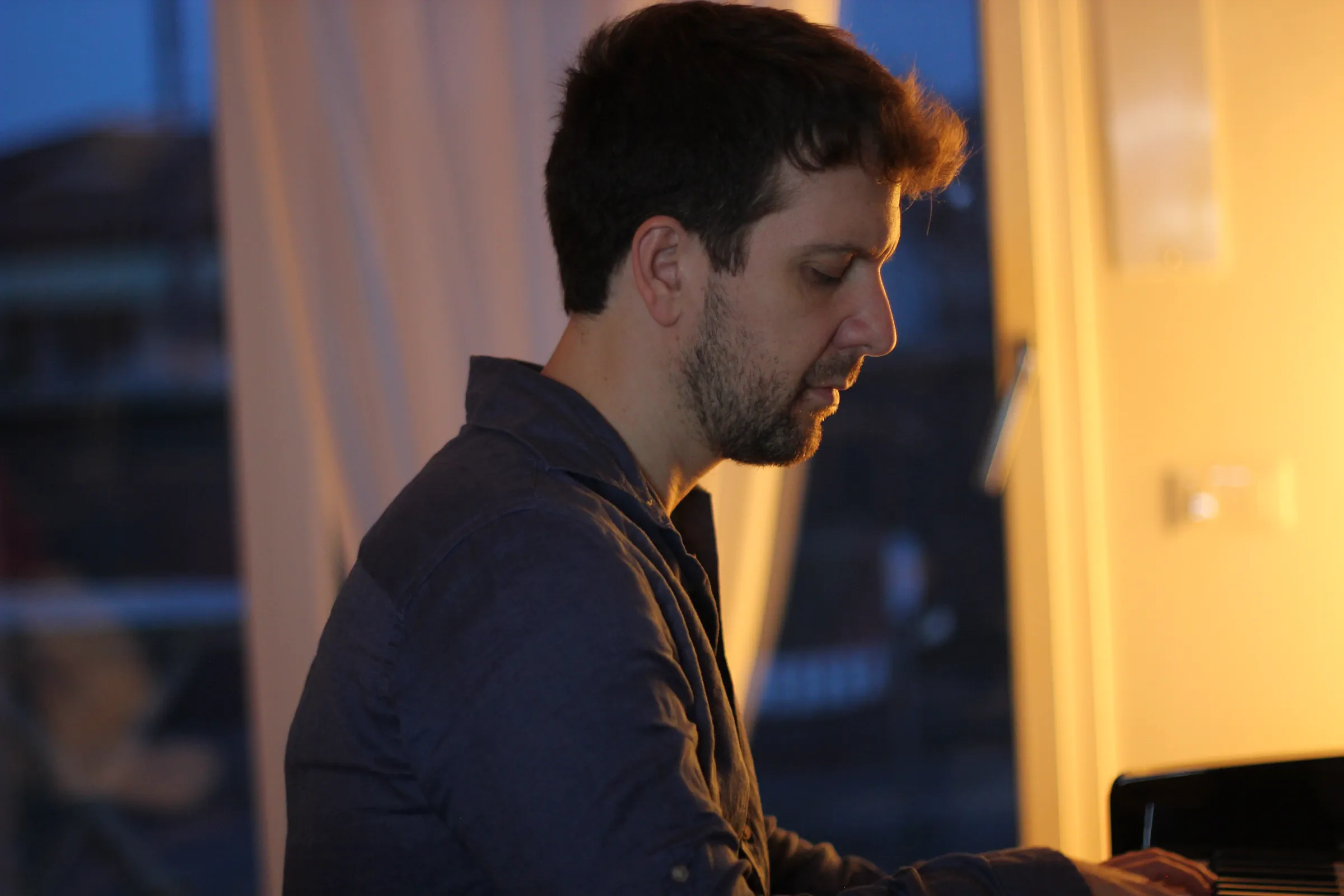 Profilo di Michele Bargigia mentre suona il pianoforte in studio.