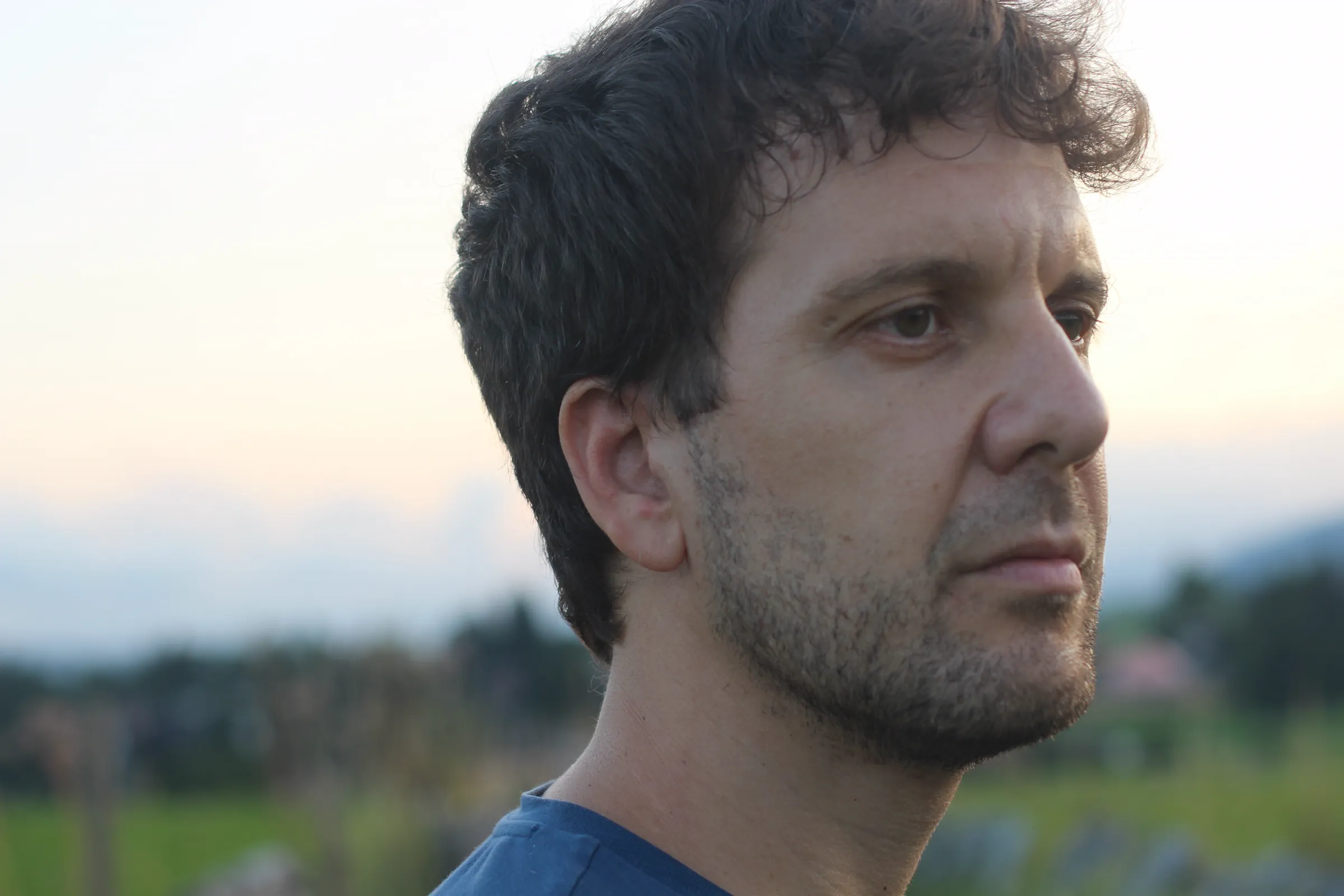 Ritratto di Michele Bargigia all’aperto davanti a una parete chiara.