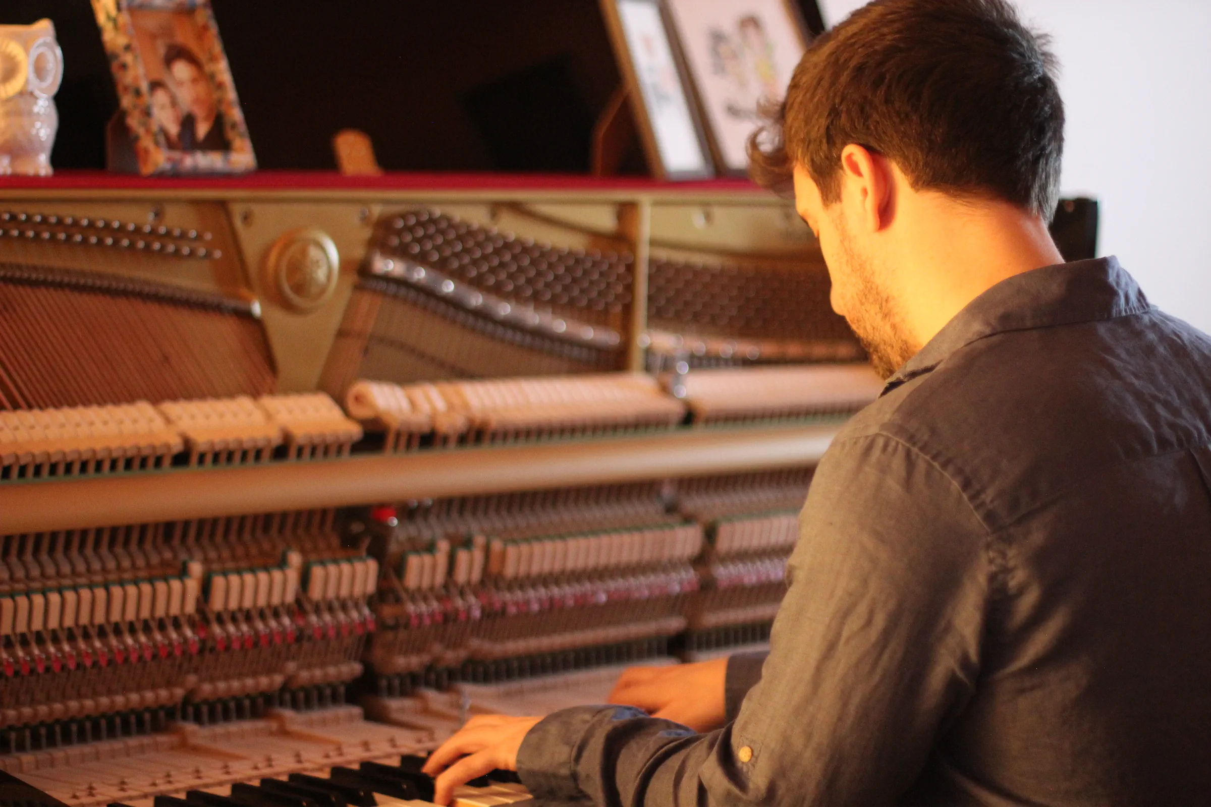 Michele Bargigia osserva il meccanismo interno di un pianoforte verticale.